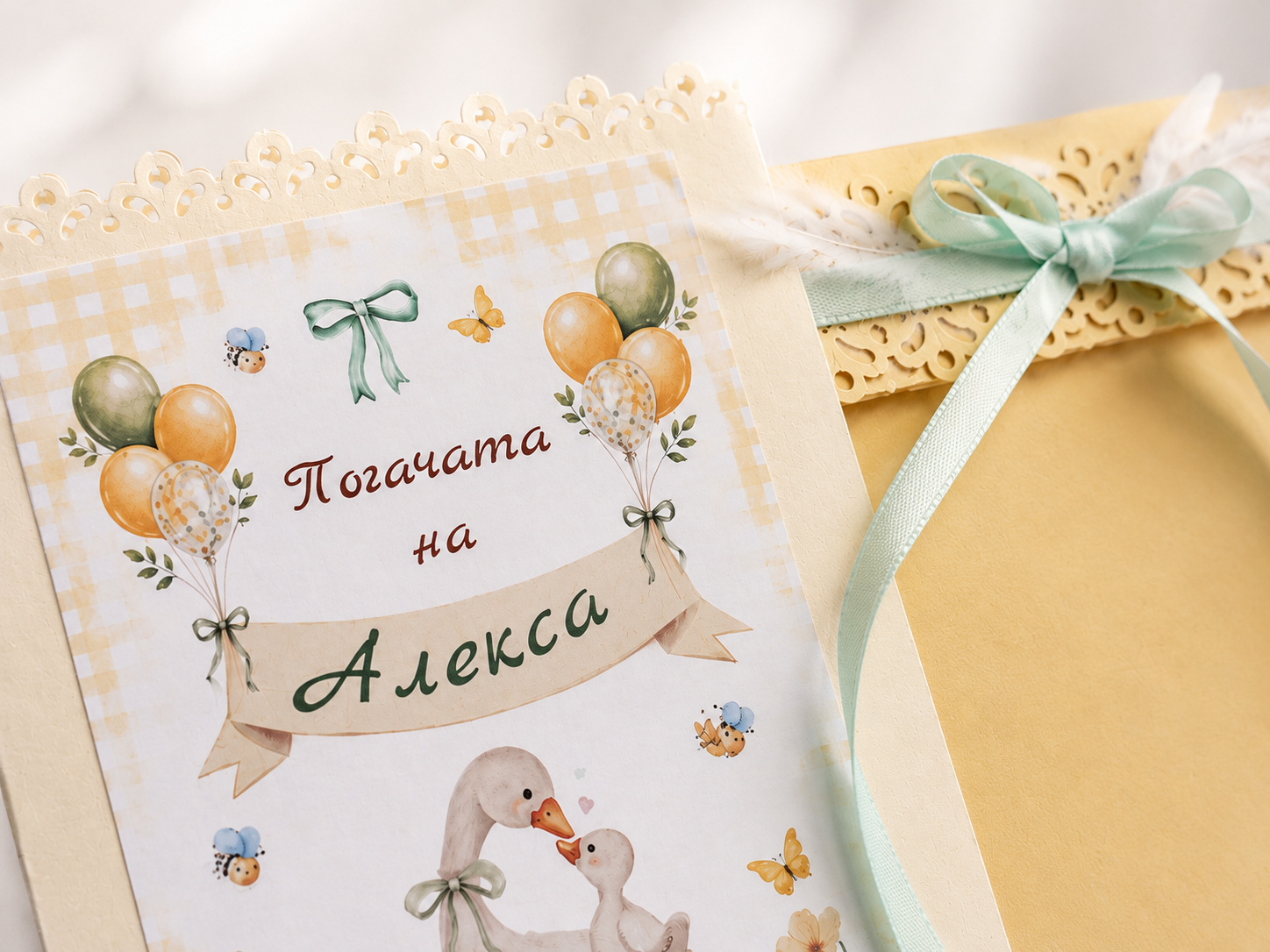 Детайл на персонализирана картичка за погача на бебе Алекса с балони, патенца и зелена панделка